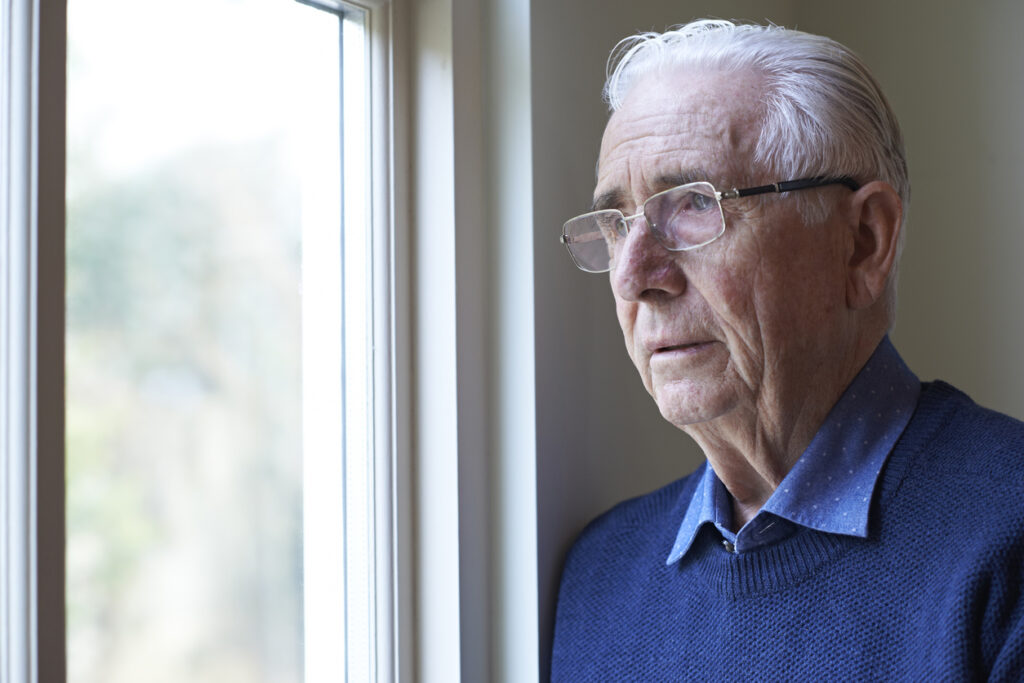 Senior Man Suffering From Depression Looking Out Of Window