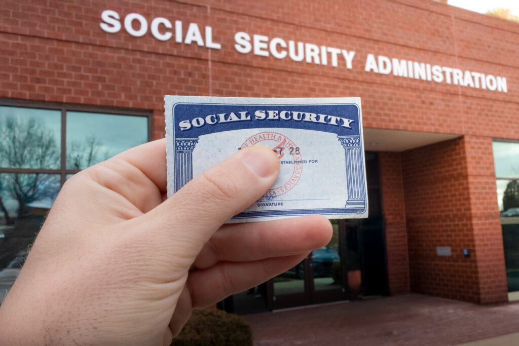 US citizen holds up social security card while waiting in line for benefits at the Social Security Administration